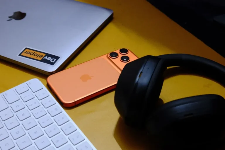 Laptop, phone, keyboard, and headphones on yellow surface