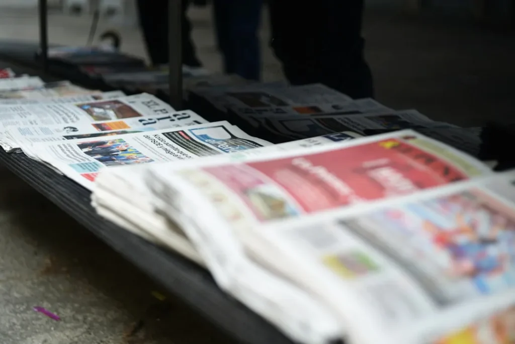 Stack of newspapers on a table outdoors.