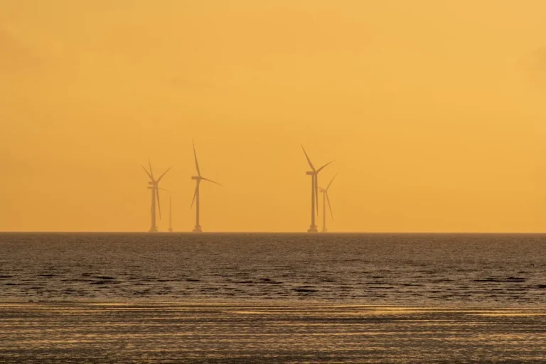 Wind turbines in the ocean at sunset